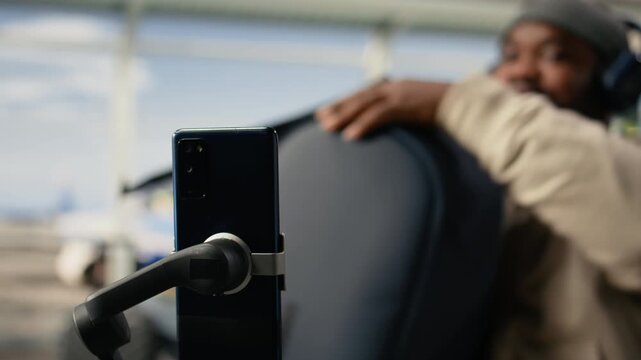 Gen Z influencer, recording video content, on smartphone with tripod, in a busy airport terminal, emphasize travel vlog storytelling. Social media freedom of a digital nomad lifestyle.