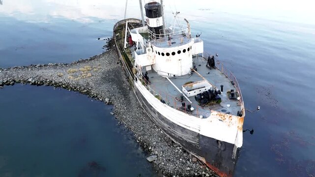 Aerial drone shot pulling back from the weathered deck and rusted hull of the Saint Christopher shipwreck grounded in the Beagle Channel, Argentina