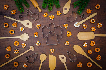 Fototapeta premium Baking holiday cookies with tools and decorations on a wooden table surrounded by pine branches