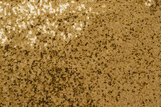 Golden sequins create a bright and shiny surface for a festive event or party in a warm setting during the evening hours