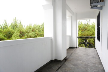 Obraz premium Empty balcony with tiled floor and view of pine trees in the background
