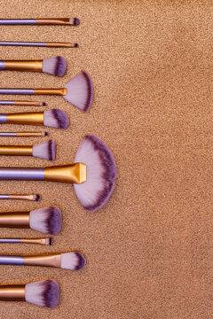 Brushes arranged on a gold background with various shapes and sizes for makeup application