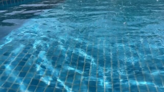 Close-up view of shimmering blue swimming pool water with tiled surface in bright sunlight