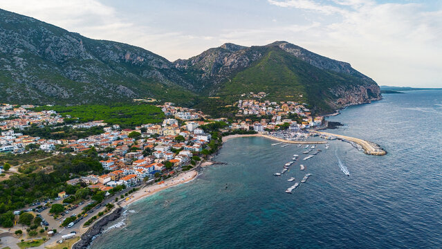 Aerial view of Cala Gonone harbor and seaside resort nestled at the foot of steep mountains, Gulf of Orosei, Sardinia, Italy
