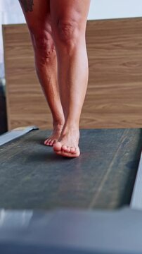 Barefoot mature woman walking with varicose veins on a treadmill