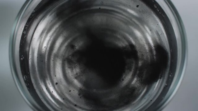 Hand pouring powder into metal container.