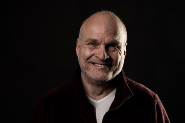 Obraz premium Middle aged bald man smiling broadly, radiating kindness and positive energy