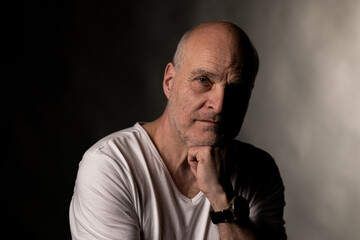 Obraz premium Bald senior man contemplating, face partially in shadow, showing deep thought