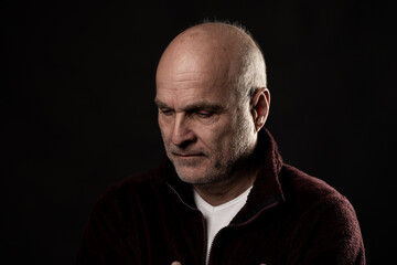 Fototapeta premium Mature man looking down, feeling disappointed and thinking in a reflective moment