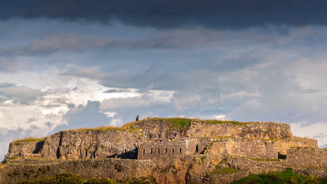 Puka Pukara Inca ruins in Cusco Peru with lone person on ancient stone fortress under dramatic sky