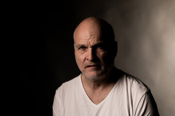 Obraz premium Man looking at camera with serious and worried expression in dark setting