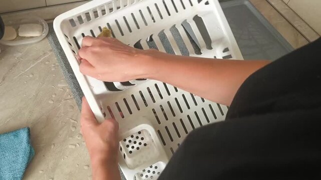Top view - a woman wipes a plastic dish dryer with a sponge on a kitchen countertop, cleaning, hygiene, cleanliness, home life.
