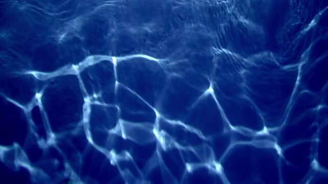 Deep blue shimmering water light pattern in aquarium tank, abstract moving background footage