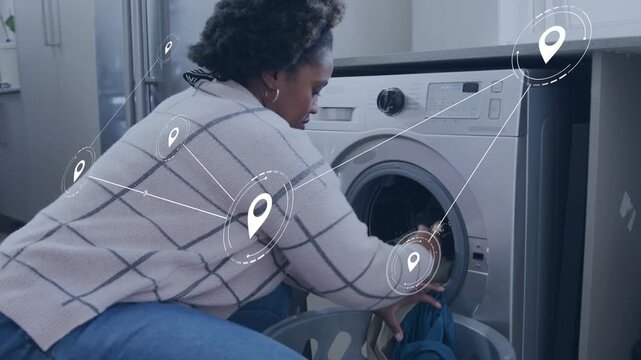 Woman kneeling by washer, opening drum and loading clothes for washing while map-pins tracking