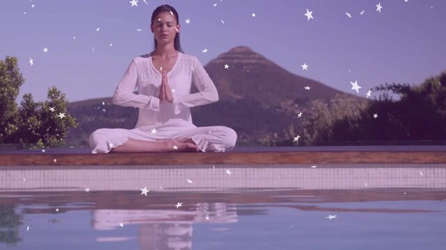 Vertical video: Sitting teen praying and meditating at pool deck, wearing white, mountain and stars
