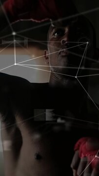 Vertical video: Male athlete raising red wrap fist preparing for training HUD nodes tracking upward