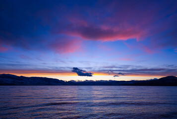 Fototapeta premium Vibrant blue and purple coastal scene with mountains and clouds