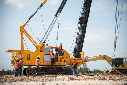 Engineer and foreman looking at heavy machine Assembly concrete pile driving truck  for  working against building construction crane