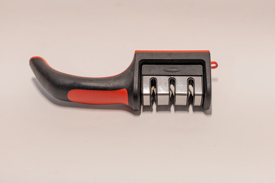 Manual 3-stage knife sharpener with ergonomic red and black handle on white background.