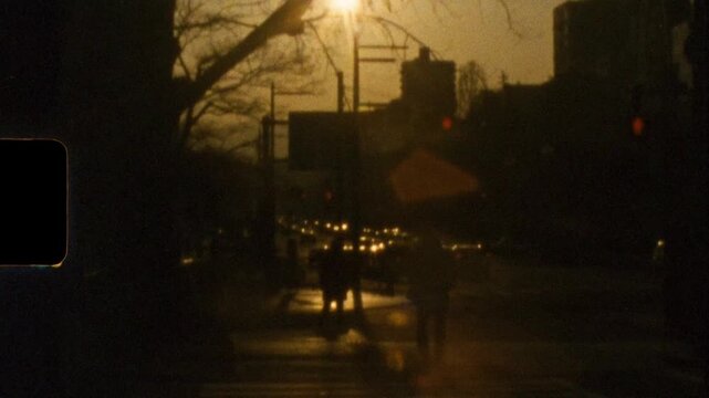 Super 8 mm vintage film of people silhouettes standing at a busy urban crossing intersection with car traffic and afternoon sunset along Peace Boulevard in Hiroshima city Japan Asia tourism and travel
