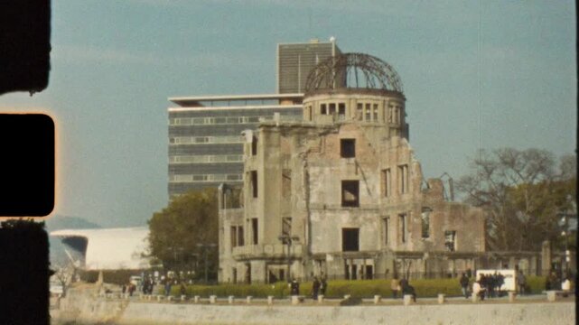 Super 8 mm vintage film of tourists near the Genbaku Dome landmark building along the foreshore waterfront of the Motoyasu River at Peace Memorial Park in Hiroshima city Japan Asia tourism and history