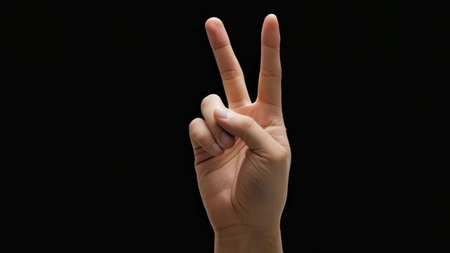 Hand making peace sign gesture against a black background.