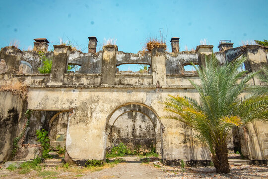 Crumbling Colonial Ruins with Arched Gate and Palm Tree at Van den Bosch Fort, Ngawi, Indonesia