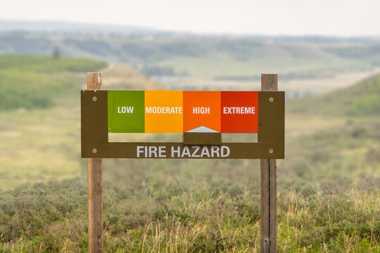 Fire hazard sign with indicator pointing to high risk in a rural park, warning of potential wildfire danger during the dry season.