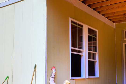 Worker is applying installing siding to t outside wall of house during home improvement task