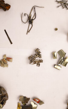 Abstract flat lay of dismantled metal pieces and bent hardware forming a raw industrial pattern on a clean white background