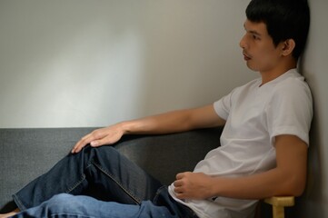Obraz premium Thoughtful young man sitting on couch in casual home setting
