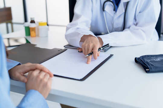 Doctor explaining treatment plan and obtaining informed consent while patient signing consent form in hospital.