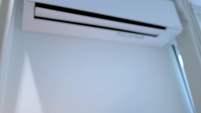 Hand Holding Remote Control to Adjust Wall Mounted Air Conditioner Temperature