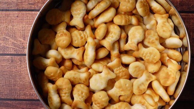 Enjoying fish-shaped snacks in a bowl on a wooden table