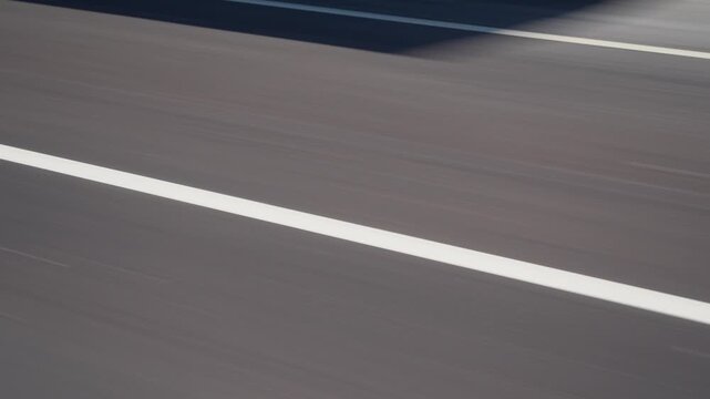 A broken line of white road markings. Close-up in motion.