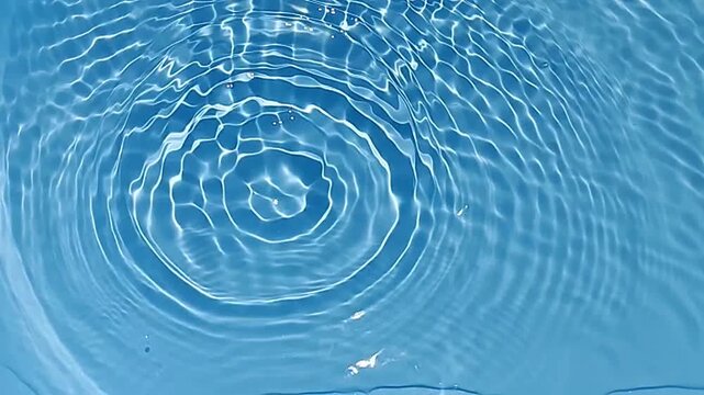 Blue water with ripples on the surface. Defocus blurred transparent blue colored clear calm water surface texture with splashes and bubbles. Water waves with shining pattern texture background.