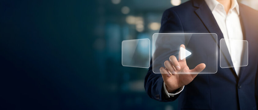 Businessman pushing play button on holographic transparent interactive touch screen interface symbolizing media streaming and digital control