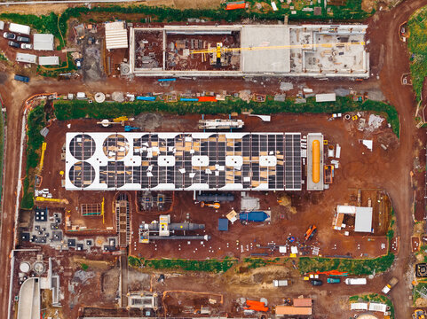 Aerial view of Pico Vermelho Geothermal Power Station with solar panels and industrial machinery on reddish soil in Conceicao, Acores, Portugal.