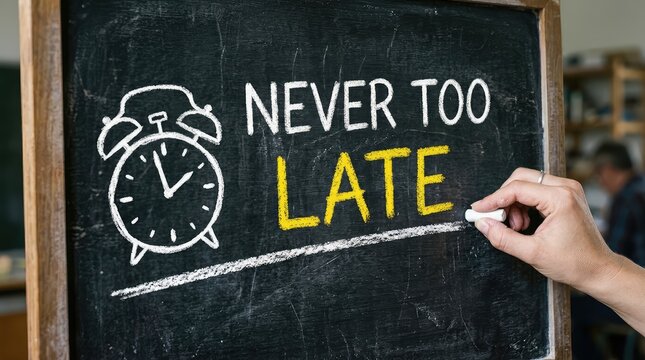 Hand writes the motivational message Never Too Late and an alarm clock on a blackboard