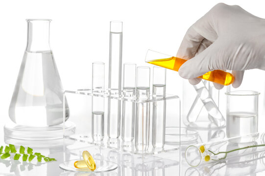 Scientist hand pouring herbal extract into test tubes with fresh herbs, botanical laboratory research on white background
