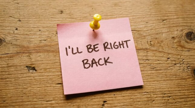 Pink reminder note saying Ill be right back pinned to a rustic wooden background