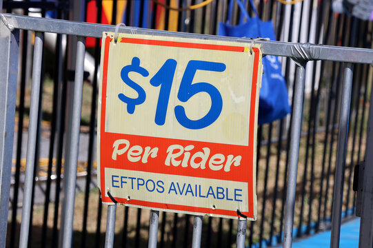 Fairground ride pricing sign showing $15 per rider with EFTPOS available on a metal safety fence at an Australian carnival