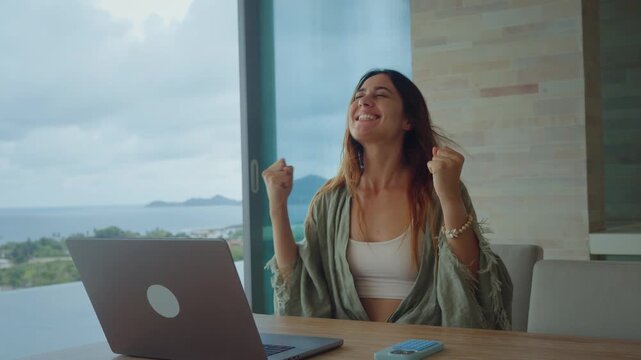 Business win moment as a woman reacts emotionally to success on her laptop. Business win energy fills the modern home office with confidence and motivation.
