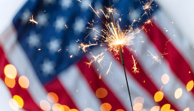 Sparkler burning brightly against a blurred american flag background