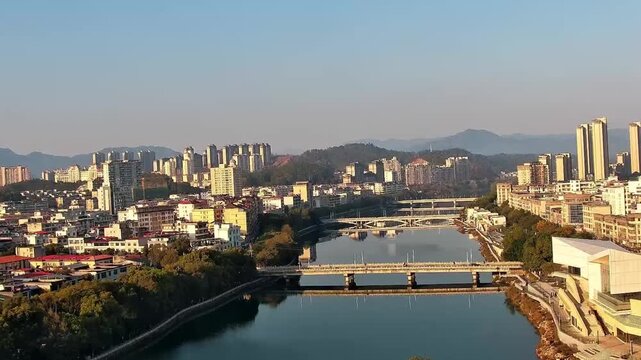 Stunning landscape showing multiple bridges crossing a calm river in Zunyi city surrounded by dense residential buildings and hills.