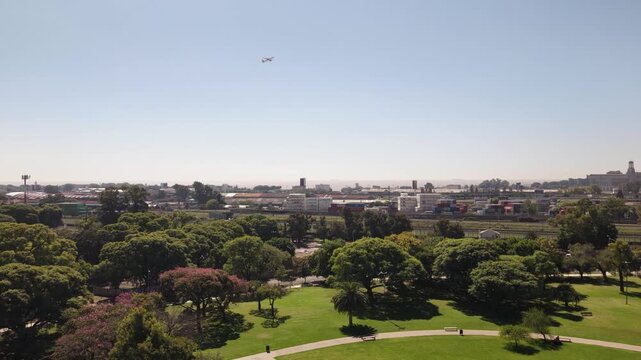 Aerial pan following a passenger aircraft departing Aeroparque Jorge Newbery (AEP) over the Port of Buenos Aires and urban parkland in Retiro, Argentina