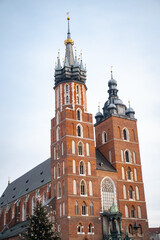 Obraz premium The brick Gothic towers of St Marys Basilica rise against a clear bright sky in Krakow. The image captures historic European architecture and cultural heritage tourism.