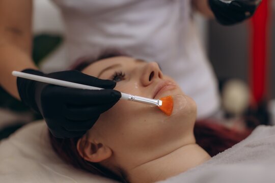 Woman receiving facial skincare mask treatment brush application