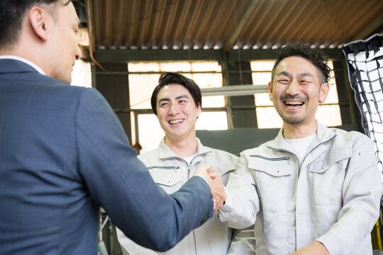 製造業の工場で握手する営業マンと作業員の信頼関係ビジネス契約や合意シーン　業務提携、協力、融資などのbtobの法人営業イメージクローズカメラ目線アップ