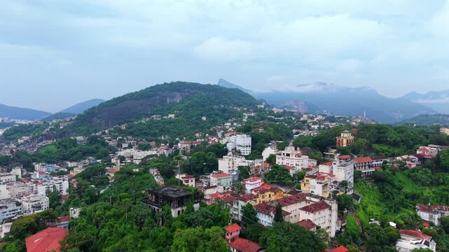 Santa Teresa neighborhood in Rio de Janeiro Brazil with colonial houses and dense Atlantic Forest vegetation on hillside above Centro with views toward Serra do Mar mountains, drone forward glide shot